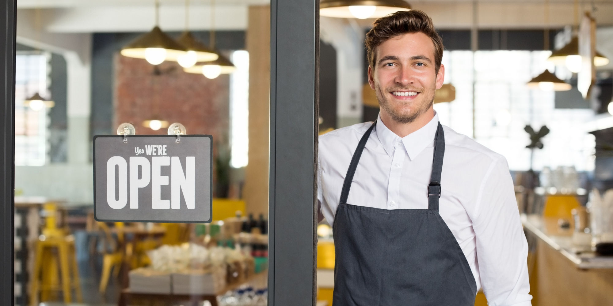 Employee standing next to Open sign on window